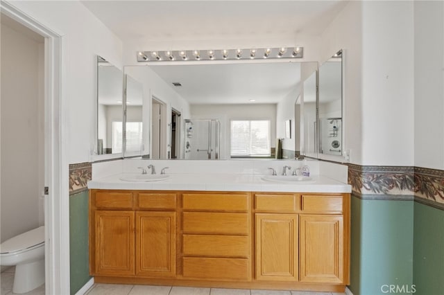 bathroom with double vanity, a sink, toilet, and a shower stall