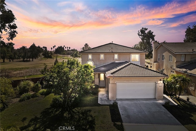 view of front of house featuring a chimney, stucco siding, concrete driveway, an attached garage, and a tiled roof