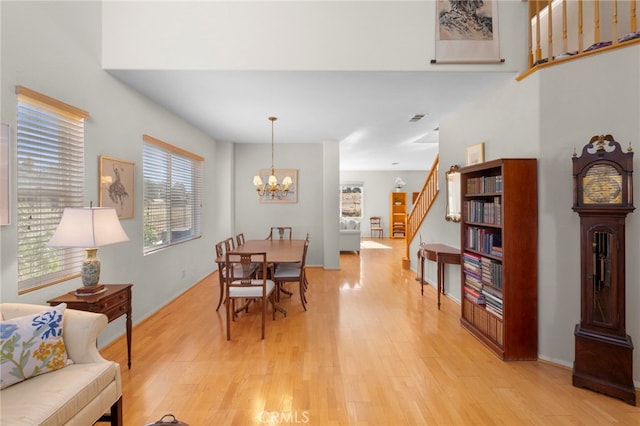 dining space with stairs, visible vents, light wood-style flooring, and a notable chandelier