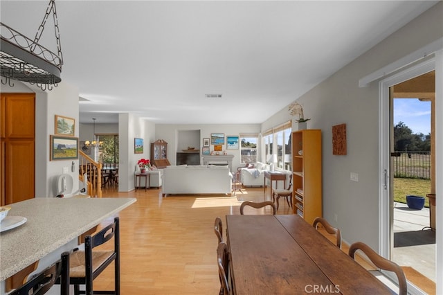 dining area featuring light wood finished floors, stairs, visible vents, and an inviting chandelier