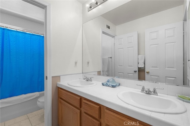 bathroom featuring double vanity, tile patterned flooring, a sink, and toilet