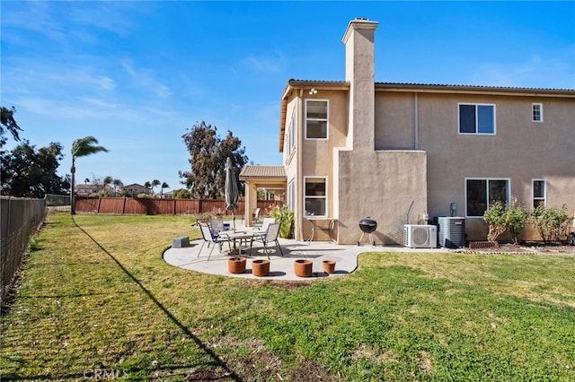 back of property with a yard, a chimney, a patio, stucco siding, and a fenced backyard