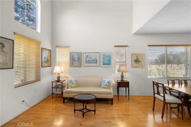 sitting room featuring light wood-style flooring and a towering ceiling