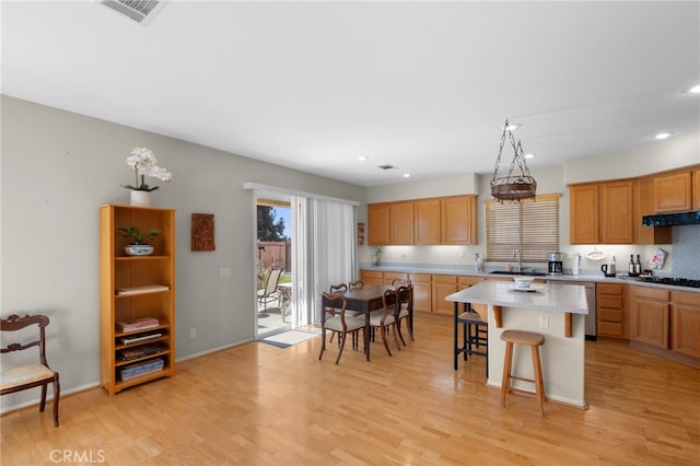 kitchen featuring under cabinet range hood, light countertops, and light wood finished floors