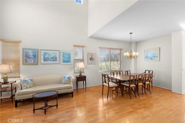 dining area featuring light wood-style floors, visible vents, a high ceiling, and an inviting chandelier