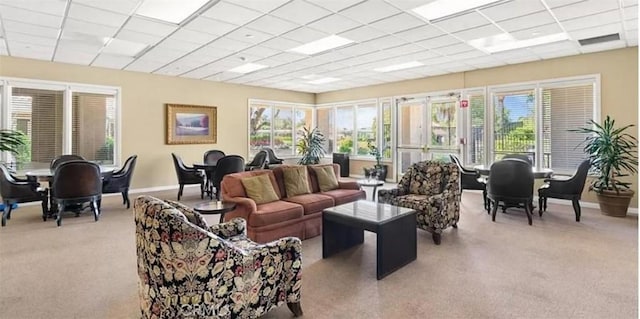 living room with light carpet, visible vents, baseboards, and a drop ceiling