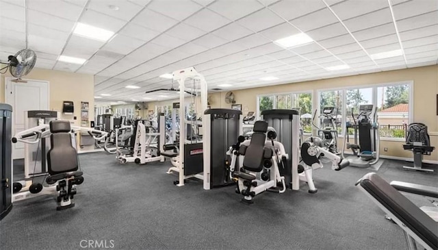 exercise room with a paneled ceiling and baseboards