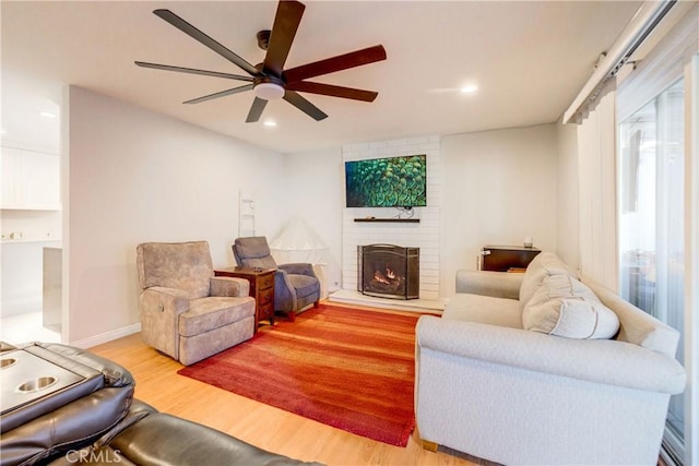 living room with ceiling fan, light wood-type flooring, and a fireplace