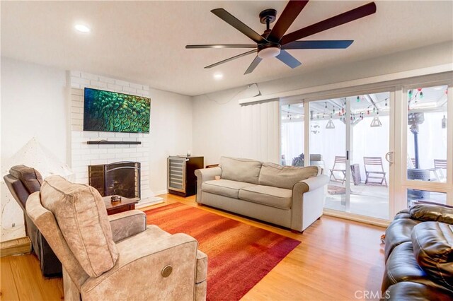 living room featuring ceiling fan, a brick fireplace, and hardwood / wood-style flooring