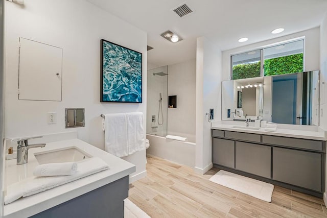 bathroom with wood-type flooring, shower / bath combination with glass door, and vanity