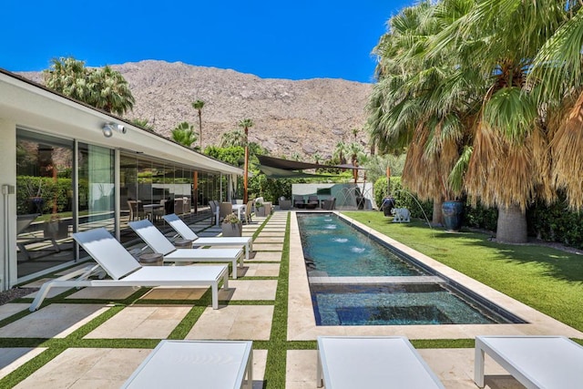 view of pool with a mountain view, a lawn, and a patio