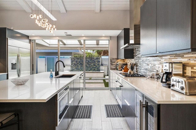 kitchen featuring decorative light fixtures, sink, a chandelier, a center island with sink, and beam ceiling