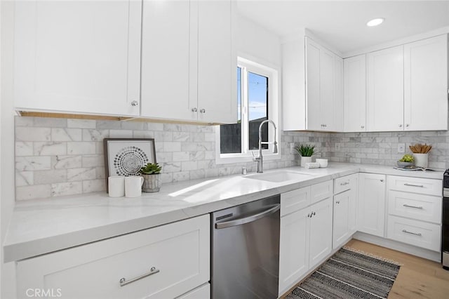 kitchen with sink, stainless steel dishwasher, tasteful backsplash, and white cabinets