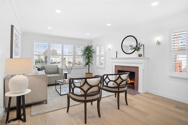 living room featuring crown molding, light wood-type flooring, and a brick fireplace