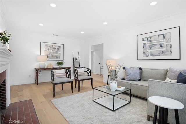 living room with crown molding, light wood-type flooring, and a brick fireplace