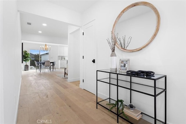 hallway featuring a notable chandelier and light hardwood / wood-style flooring