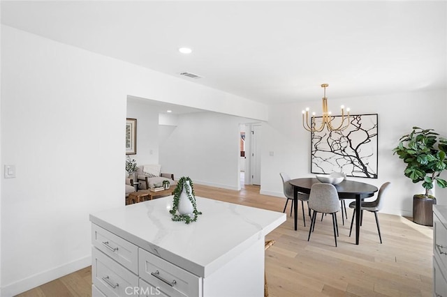 kitchen with a chandelier, light hardwood / wood-style floors, a center island, and pendant lighting