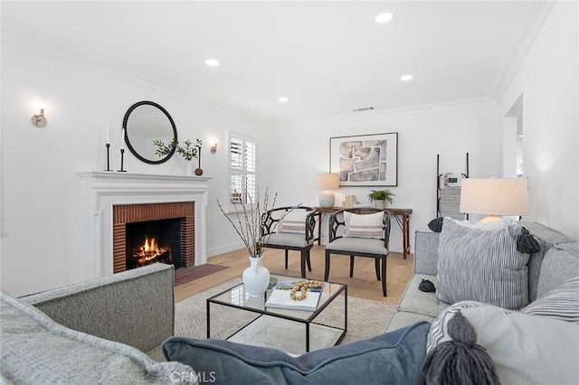 living room featuring light hardwood / wood-style flooring, ornamental molding, and a fireplace