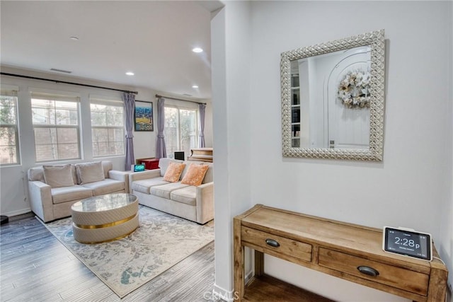 living room featuring baseboards, visible vents, wood finished floors, and recessed lighting