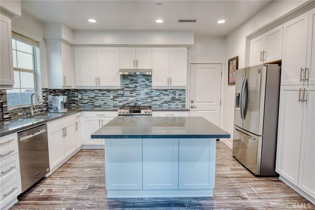 kitchen featuring a kitchen island, a sink, visible vents, appliances with stainless steel finishes, and dark countertops