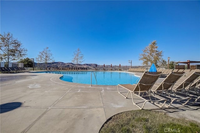 community pool featuring a patio, fence, and a mountain view