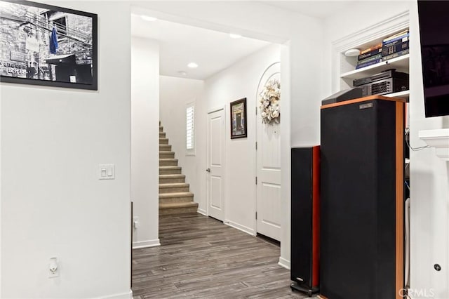 hallway featuring stairs, baseboards, wood finished floors, and recessed lighting