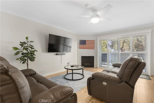 living room with light hardwood / wood-style floors, ornamental molding, ceiling fan, and a fireplace