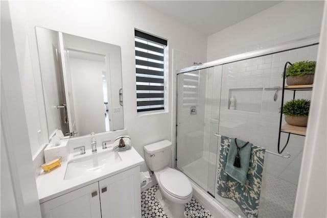 bathroom featuring a shower with shower door, toilet, and vanity