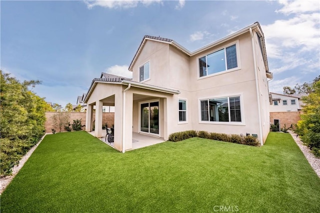 back of house with a lawn and a patio