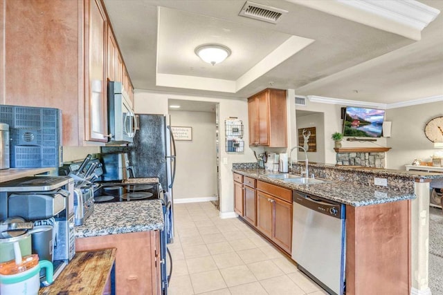 kitchen featuring stainless steel appliances, a tray ceiling, sink, dark stone countertops, and light tile patterned flooring