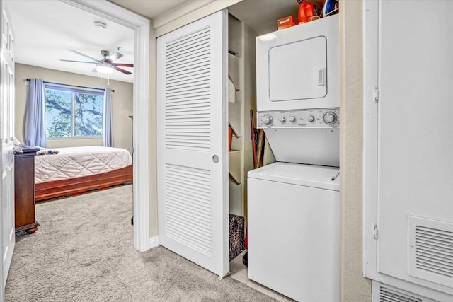 laundry room with stacked washer / drying machine, ceiling fan, and light carpet