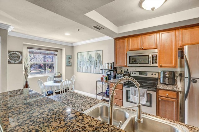 kitchen with dark stone countertops, ornamental molding, and appliances with stainless steel finishes