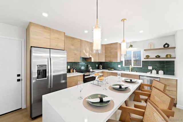 kitchen featuring a center island, stainless steel appliances, sink, hanging light fixtures, and light hardwood / wood-style flooring