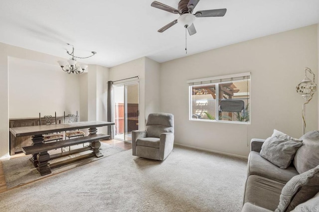 living area featuring ceiling fan with notable chandelier and light colored carpet