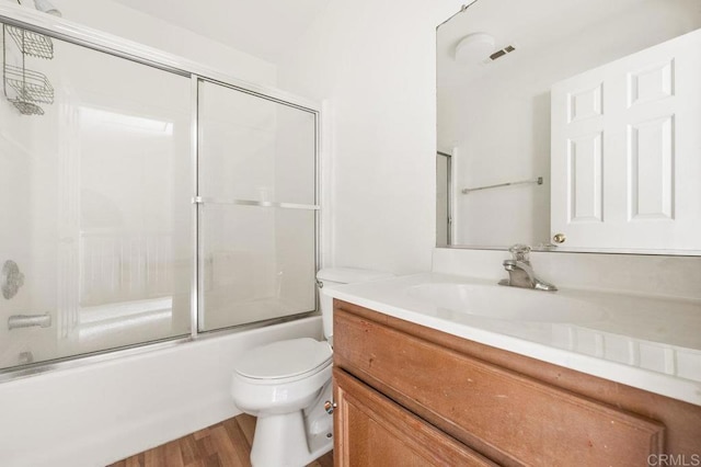 full bathroom featuring toilet, combined bath / shower with glass door, wood-type flooring, and vanity