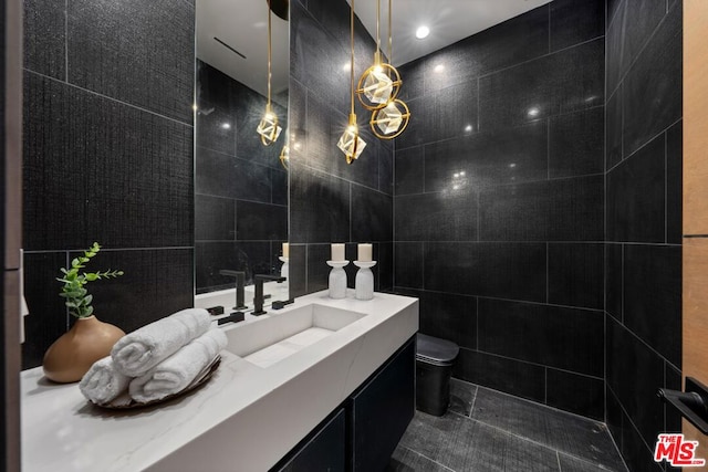 bathroom with toilet, tile walls, tile patterned floors, and vanity