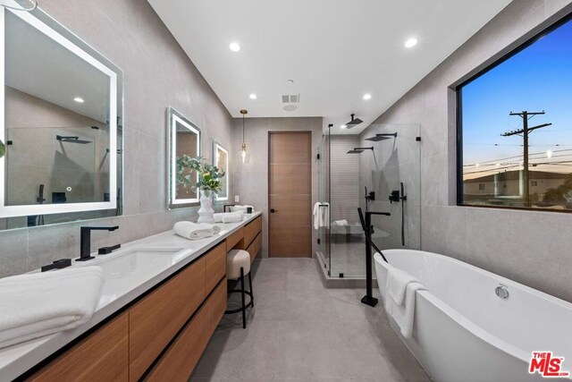 bathroom with tile walls, vanity, and shower with separate bathtub