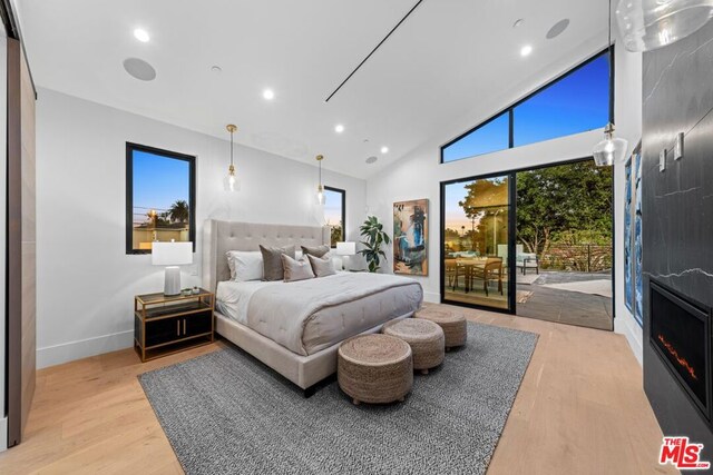 bedroom with high vaulted ceiling, access to exterior, and light hardwood / wood-style floors