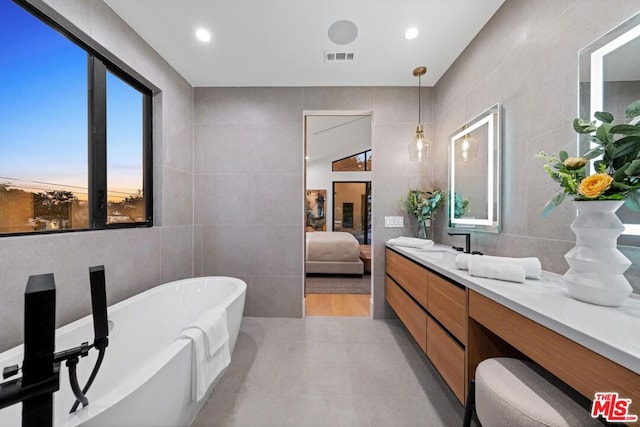 bathroom with a bathing tub, tile walls, and vanity