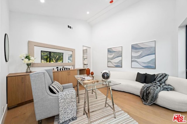 living room featuring high vaulted ceiling and light wood-type flooring