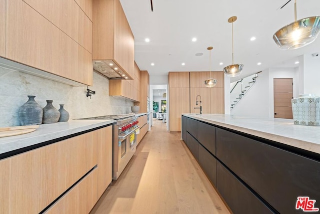 kitchen with light wood-type flooring, light brown cabinets, hanging light fixtures, and range with two ovens