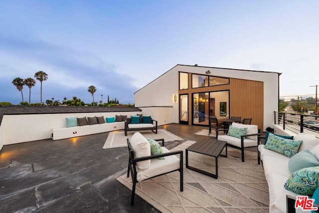 patio terrace at dusk with a balcony and an outdoor hangout area