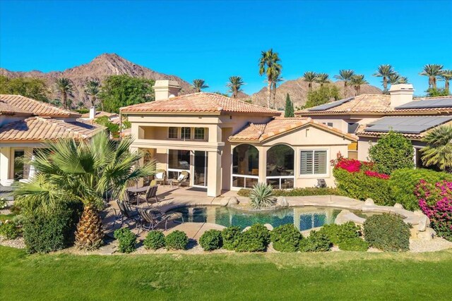 back of house with a patio area, a mountain view, and a yard