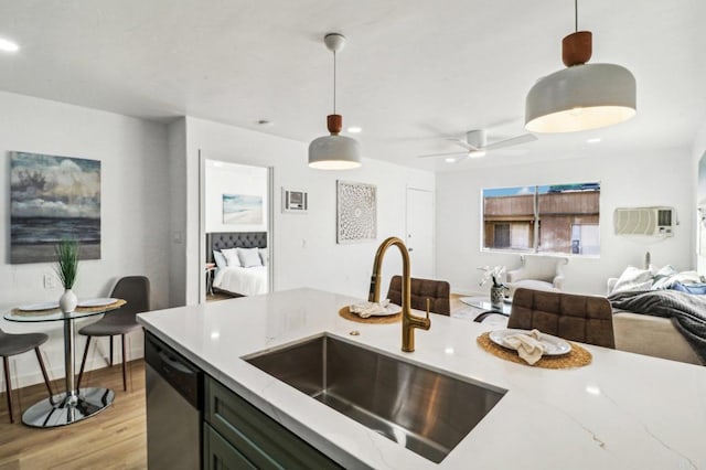 kitchen with pendant lighting, dishwasher, light stone counters, and sink