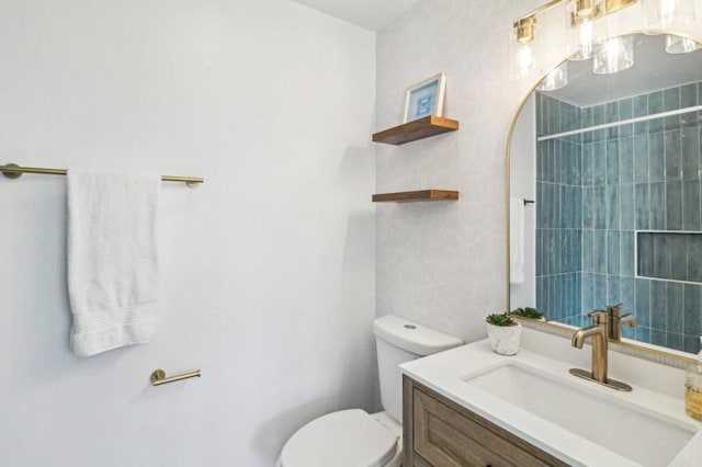 bathroom with toilet, vanity, and a tile shower