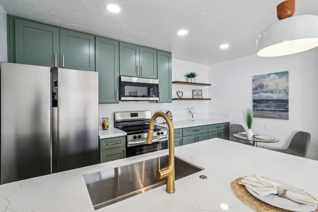 kitchen with stainless steel appliances, light stone counters, and green cabinetry