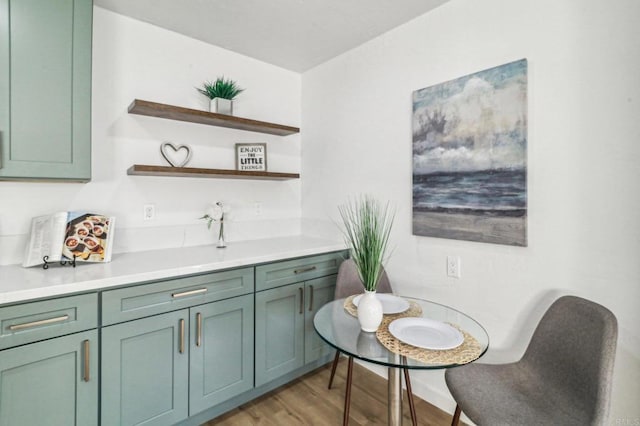 bar featuring light wood-type flooring and green cabinets