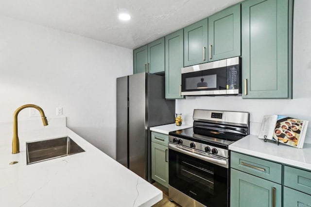 kitchen featuring light stone countertops, sink, green cabinets, and stainless steel appliances