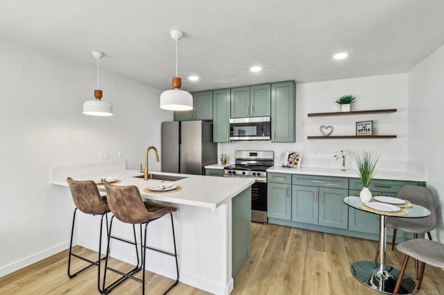 kitchen with kitchen peninsula, sink, hanging light fixtures, appliances with stainless steel finishes, and a breakfast bar area