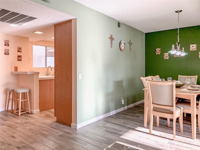 dining area featuring wood-type flooring, sink, and a textured ceiling